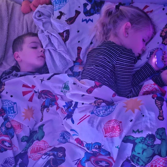 Un frère et une sœur endormis dans le même lit ; la petite fille tient son CalmKid.